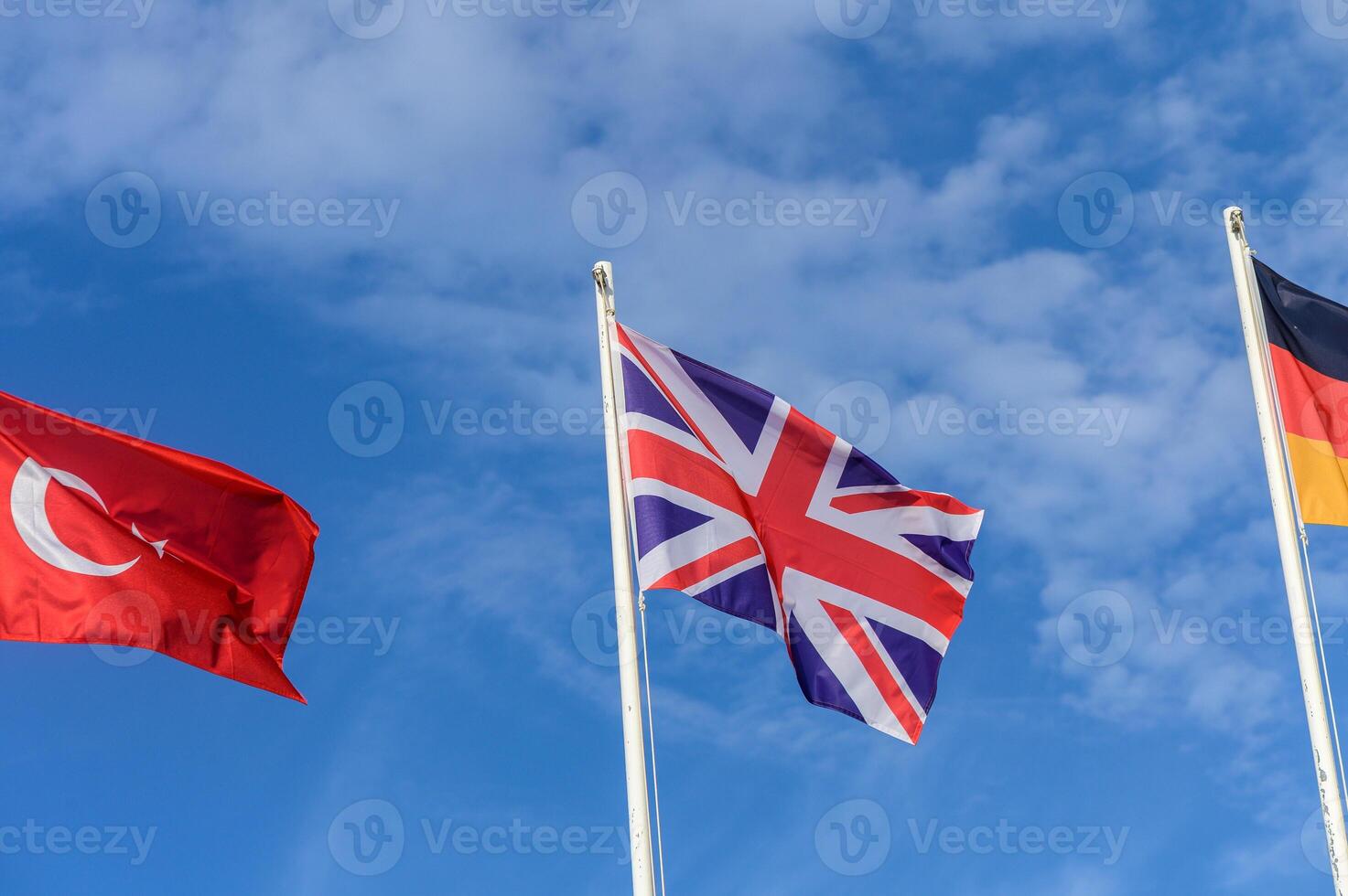 Three vibrant flags waving proudly against a bright blue sky on a sunny day, representing international unity and diversity photo