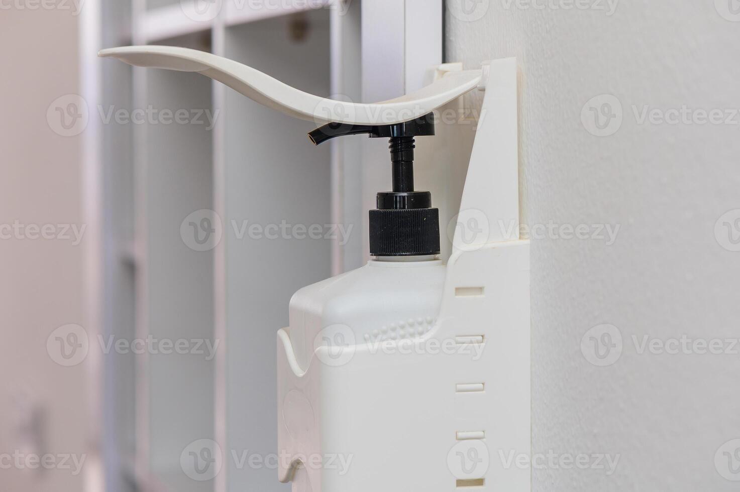 A Sleek White Hand Sanitizer Dispenser Mounted on a Wall in a Modern Indoor Setting for Promoting Hygiene and Cleanliness photo