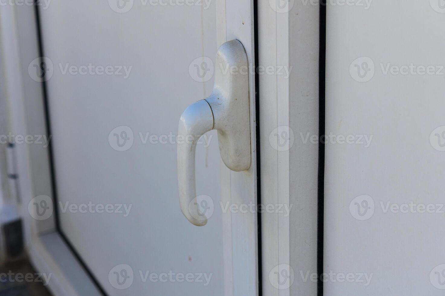 A Close-Up View of a White Door Handle Shining Under Bright Daylight, With Delicate Textures Highlighting Its Simplicity and Design photo