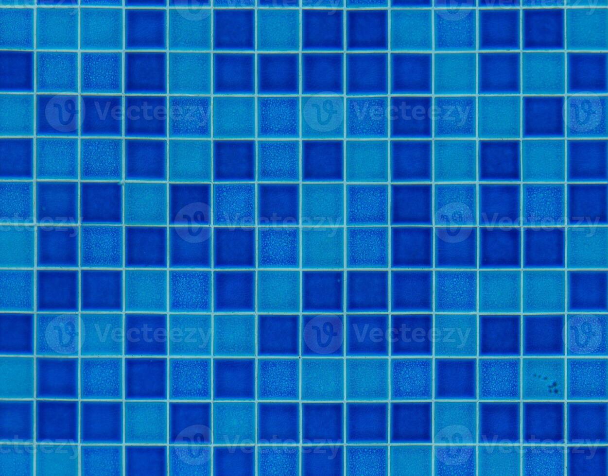 Vibrant blue mosaic tiles create a calming atmosphere in a tranquil swimming pool area during midday sunlight photo