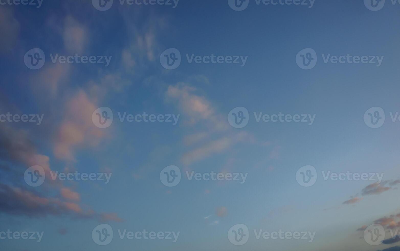 A tranquil evening sky filled with soft clouds above a serene landscape at dusk photo