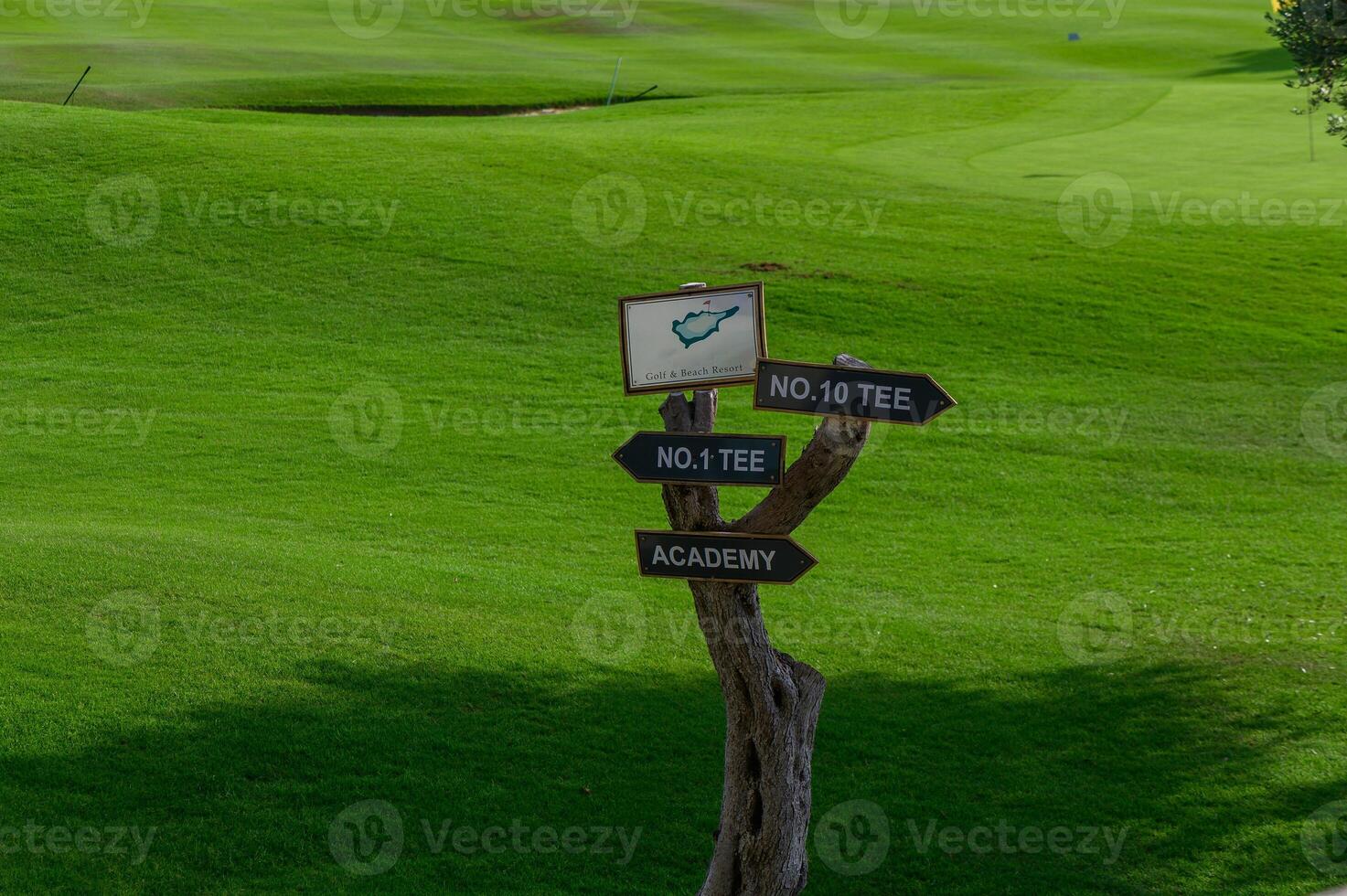 Signpost leading to the tee areas and academy on a vibrant green golf course in sunny weather photo