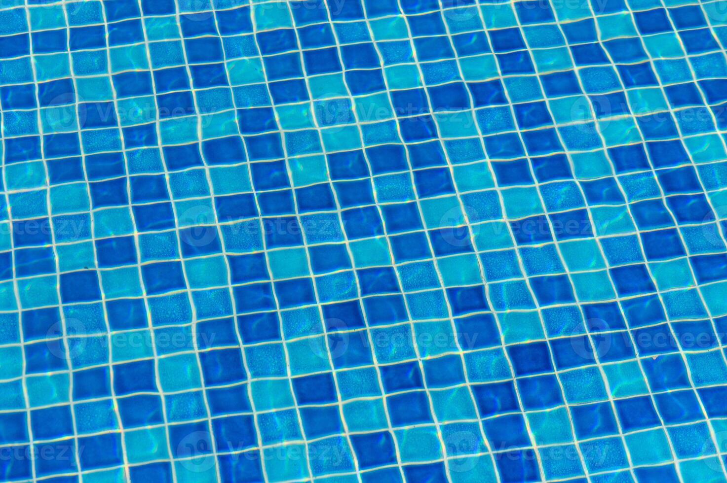 Bright Blue Tile Patterns Create a Vibrant Mosaic Beneath the Reflective Surface of a Swimming Pool on a Sunny Afternoon photo