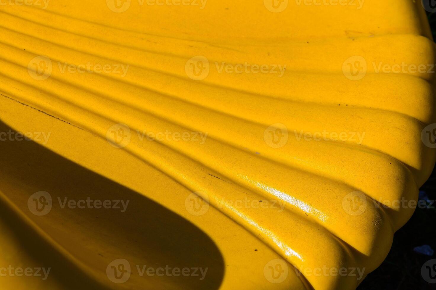 A vibrant yellow bench creates a sunny accent in a serene park setting during early afternoon, inviting relaxation and enjoyment photo