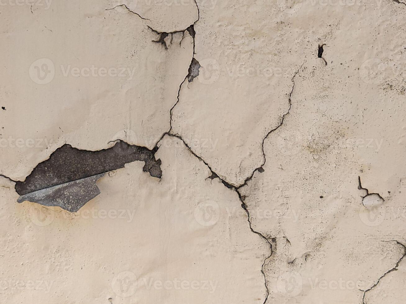A crack in a wall with a piece of metal photo