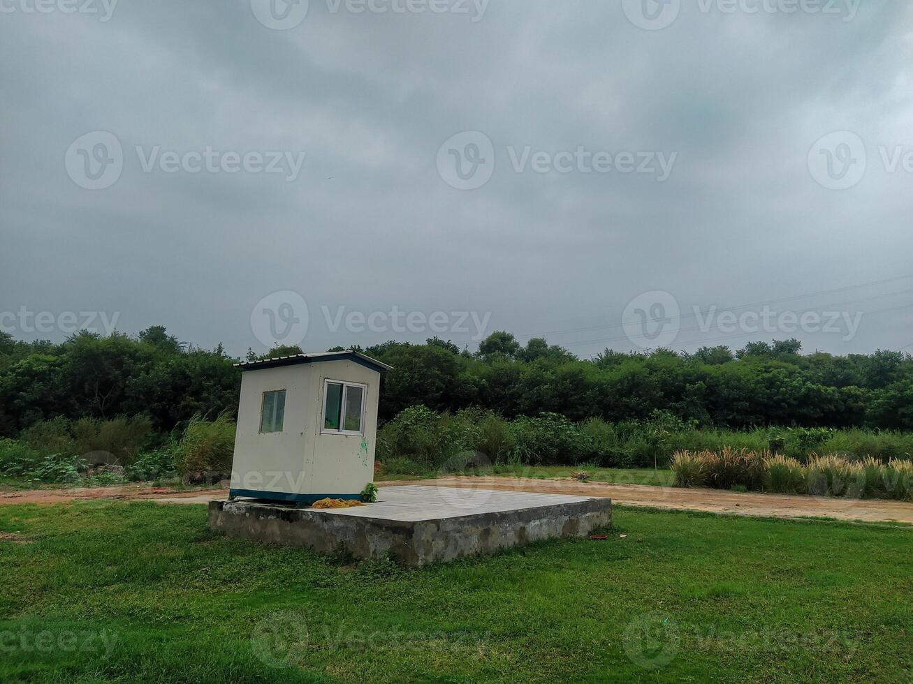 A small white building sitting on top of a grassy field photo