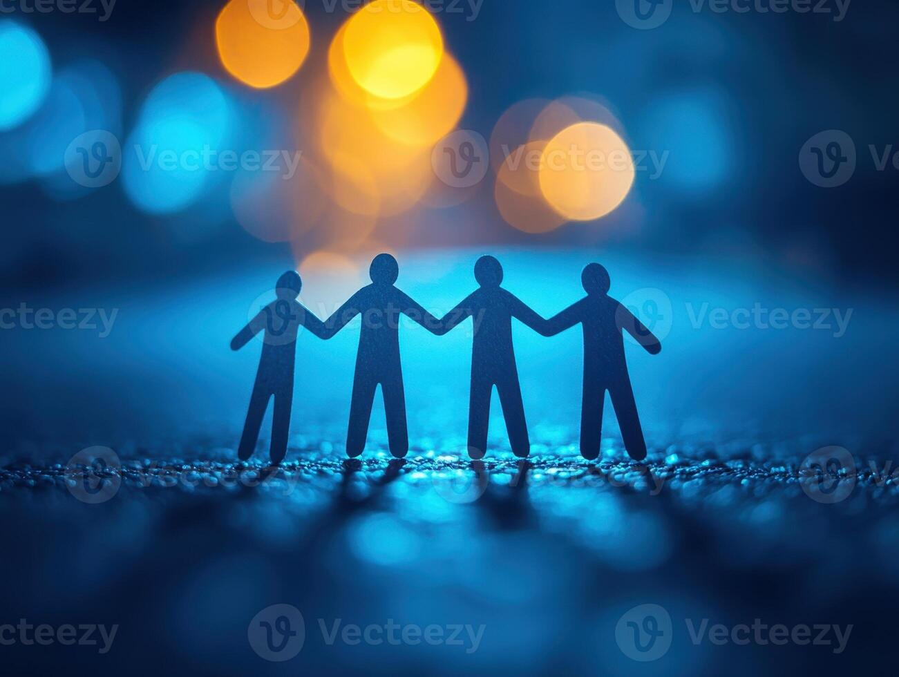 Four paper cutout figures holding hands against a blurred blue and yellow background, symbolizing friendship, unity, and connection. photo