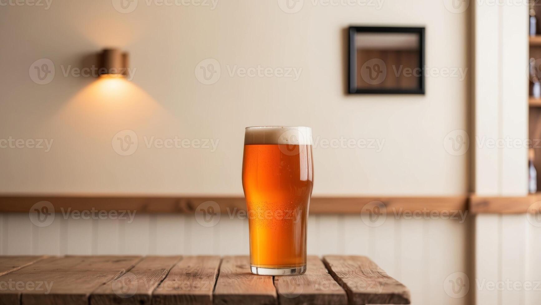 A beer glass on a wooden table in front of a wall photo