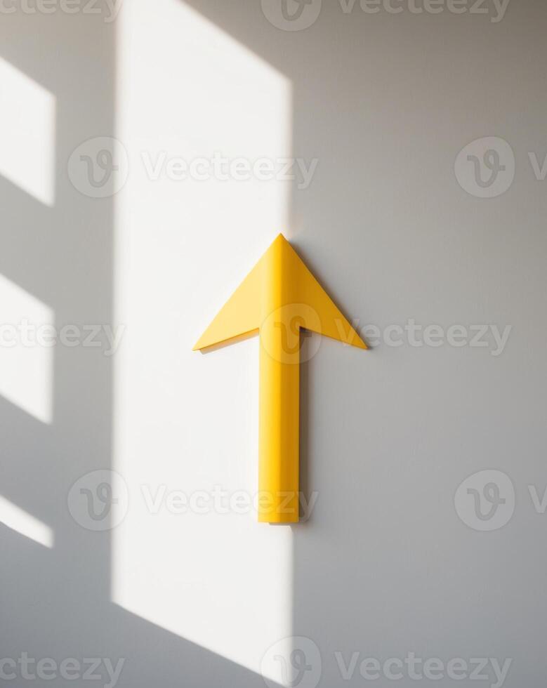 Yellow arrow pointing to the future on a white wall photo