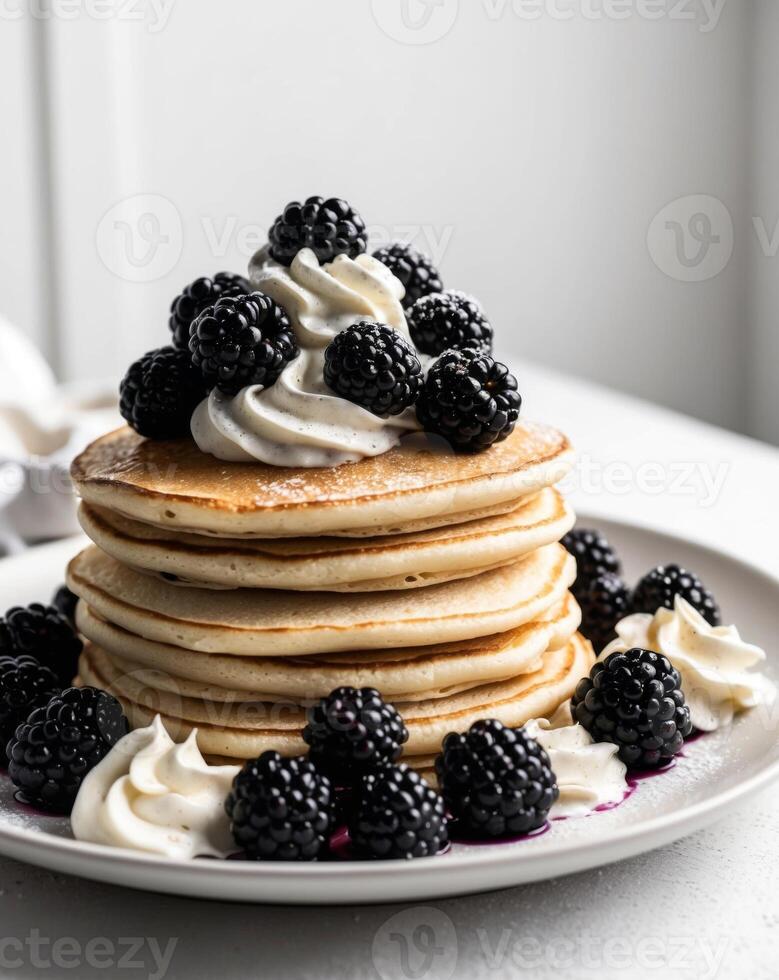 A stack of pancakes topped with whipped cream and blackberries photo