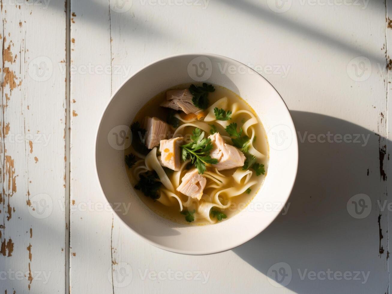 A bowl of soup with chicken and noodles photo