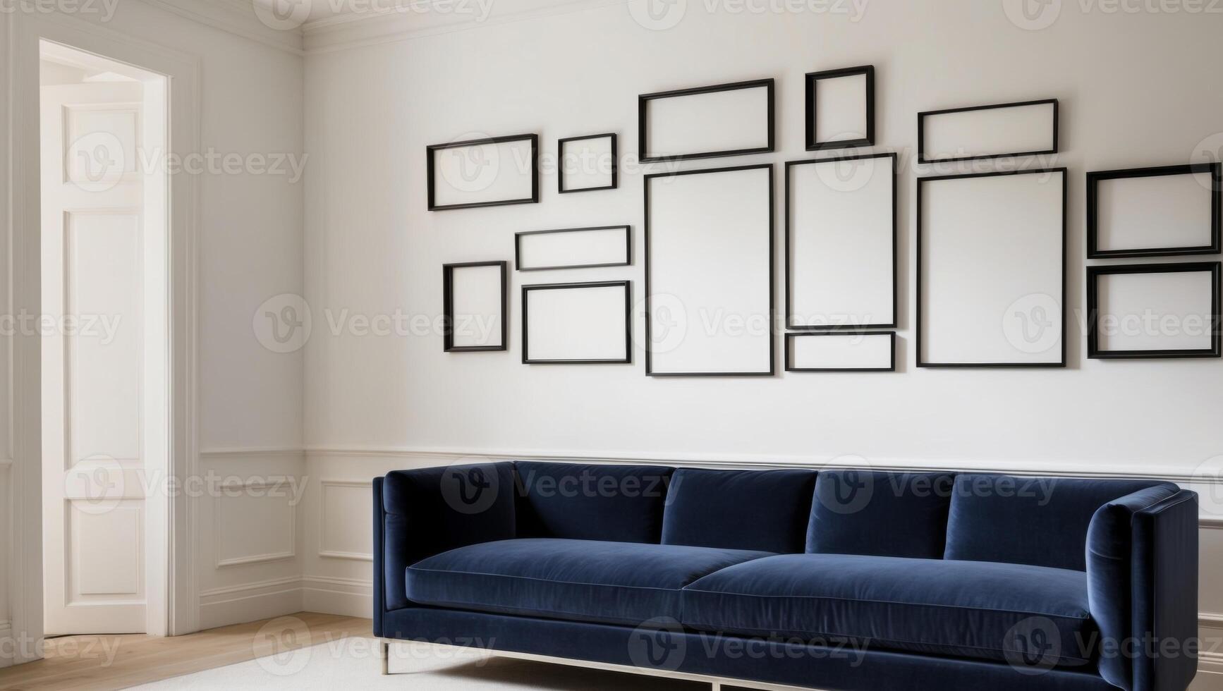 A blue velvet couch in front of a wall with framed pictures photo