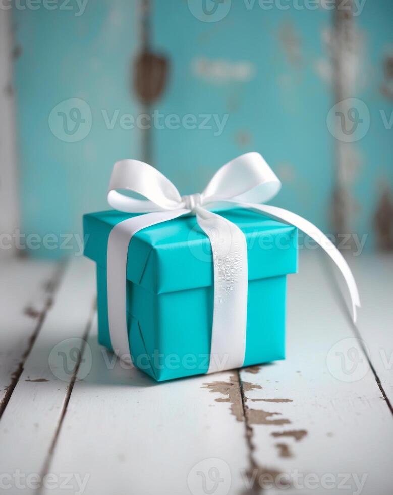 A blue gift box with a white ribbon on a wooden table photo
