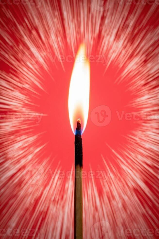 A matchstick is lit on fire in front of a red background photo