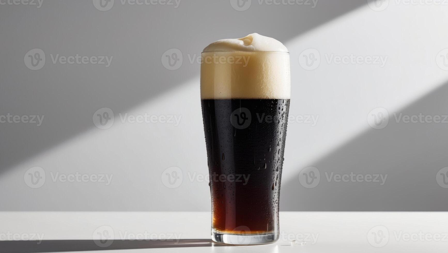 A tall glass of dark beer sitting on a table photo