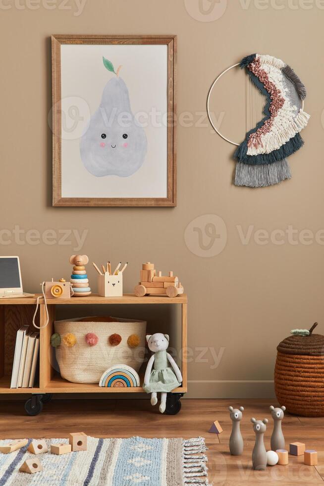 Stylish scandinavian newborn baby room with brown wooden mock up poster frame, toys, doll and child accessories. Cozy decoration and hanging macrame on the beige wall. photo