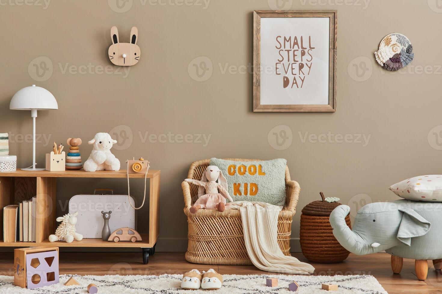 Stylish scandinavian kid room interior with toys, teddy bear, plush animal toys, rattan sofa, furniture and child accessories. Brown wooden mock up poster frame on the wall. photo