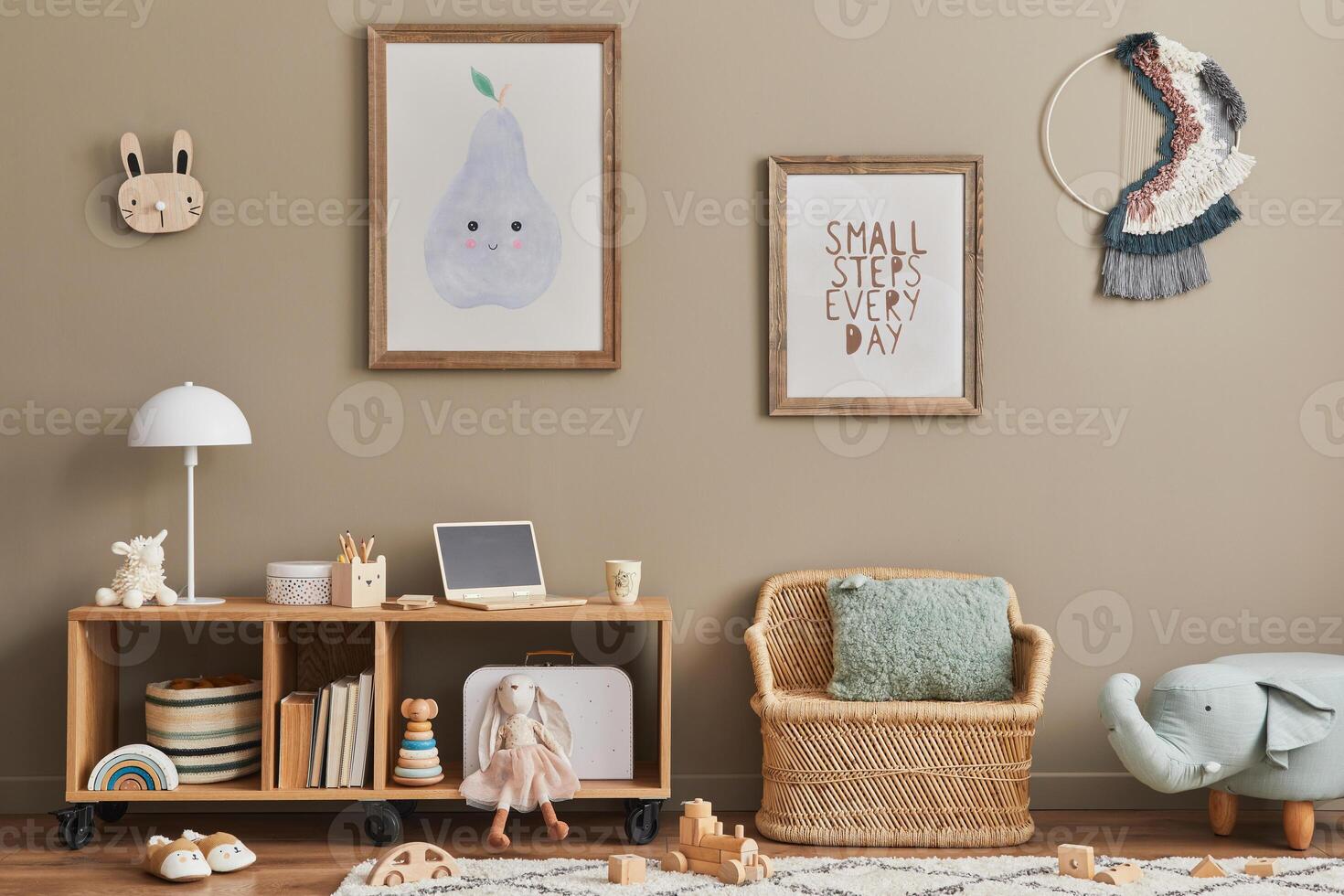 Interior of child room with mint armchair, brown mock up poster frame, toys, teddy bear, decoration and hanging cotton colorful balls. Beige wall. Warm kid space. Template. photo