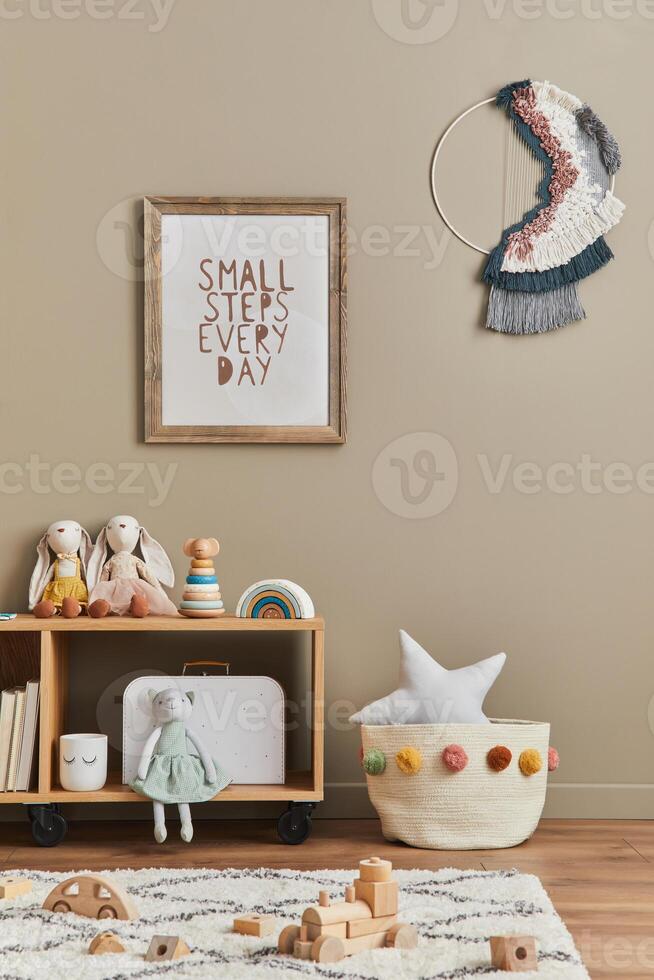 Stylish scandinavian newborn baby room with brown wooden mock up poster frame, toys, plush animal and child accessories. Decoration and hanging cotton flags on the beige wall. photo