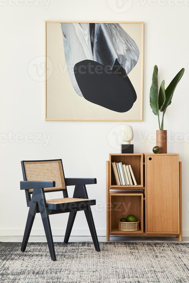 Modern composition of living room interior with design black chair, wooden bookcase, tropical leaf in vase, book, decoration and abstract painitngs on the wall. photo