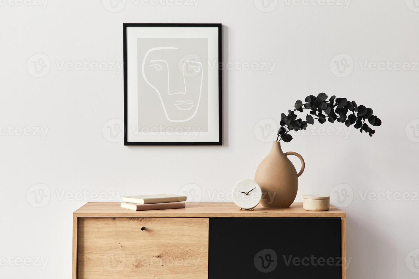 Stylish interior of living room with mock up poster frame, wooden commode, book, eucalyptus leaf in vase and elegant personal accessories. Minimalist concept of home decor. Template. photo