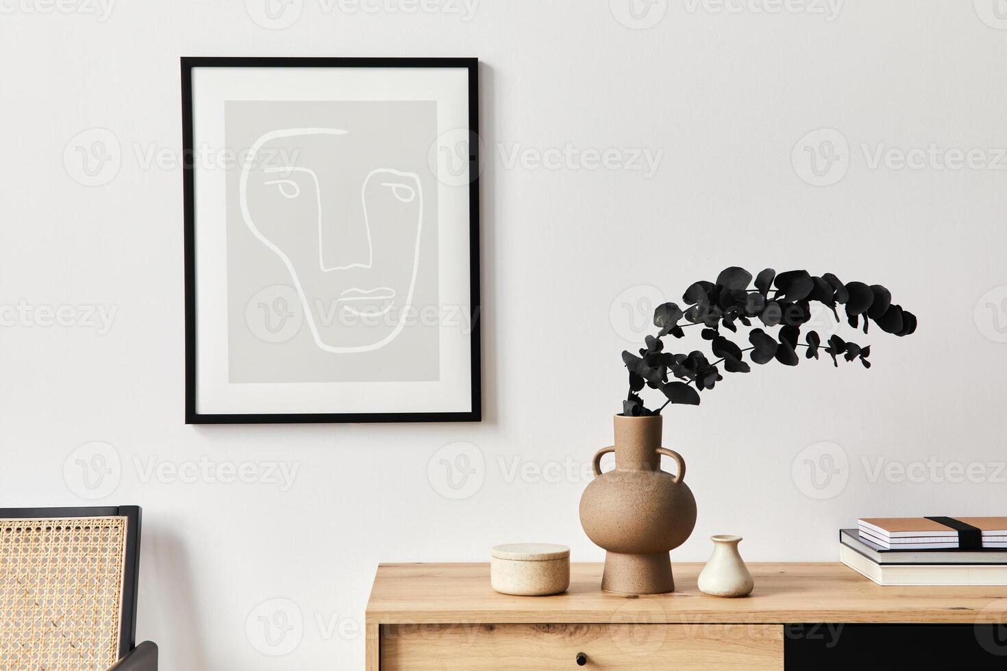 Stylish interior of living room with mock up poster frame, wooden commode, eucalyptus leaf in ceramic vase and elegant personal accessories. Minimalist concept of home decor. photo