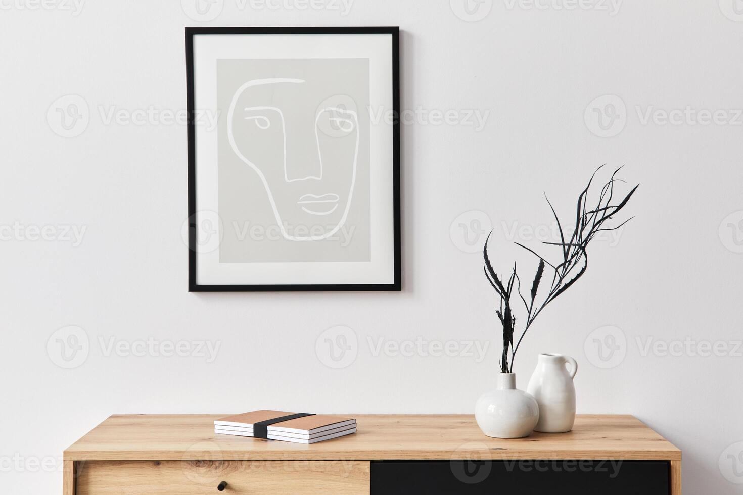 Stylish interior of living room with mock up poster frame, wooden commode, book, leaf in ceramic vase and elegant accessories. Minimalist concept of home decor. photo