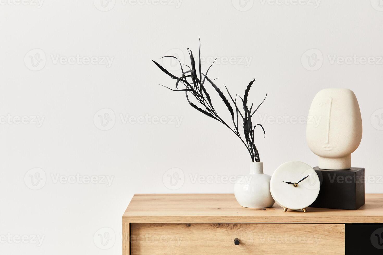 Minimalist concept of living room interior at elegant apartment with wooden commode, leaf in vase, clock and elegant personal accessories in modern home decor. Copy space. photo