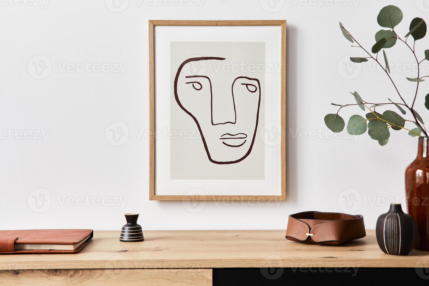 Stylish interior of living room with mock up poster frame, wooden commode, book, eucalyptus leaf in ceramic vase and elegant accessories. Minimalist concept of home decor. photo