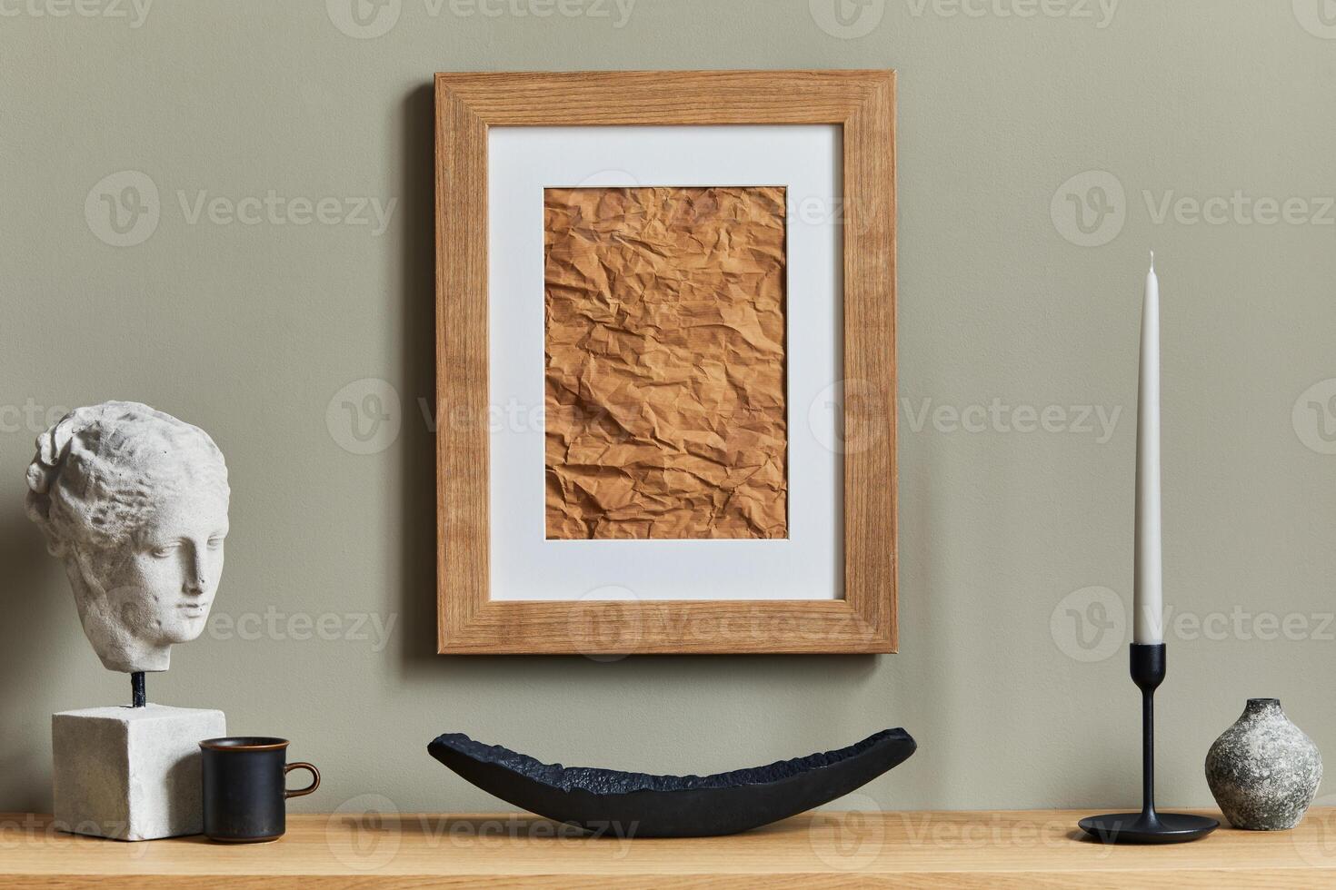 Stylish and luxury interior with wooden mock up poster frame, vases, books, stools, mug and elegant accessories in home decor. Template photo