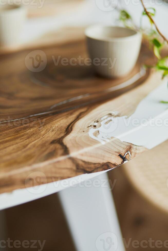 Interior design of stylish dining room with family wooden and epoxy table, rattan chairs, flowers in vase and teapot with cups. Details. Template. photo