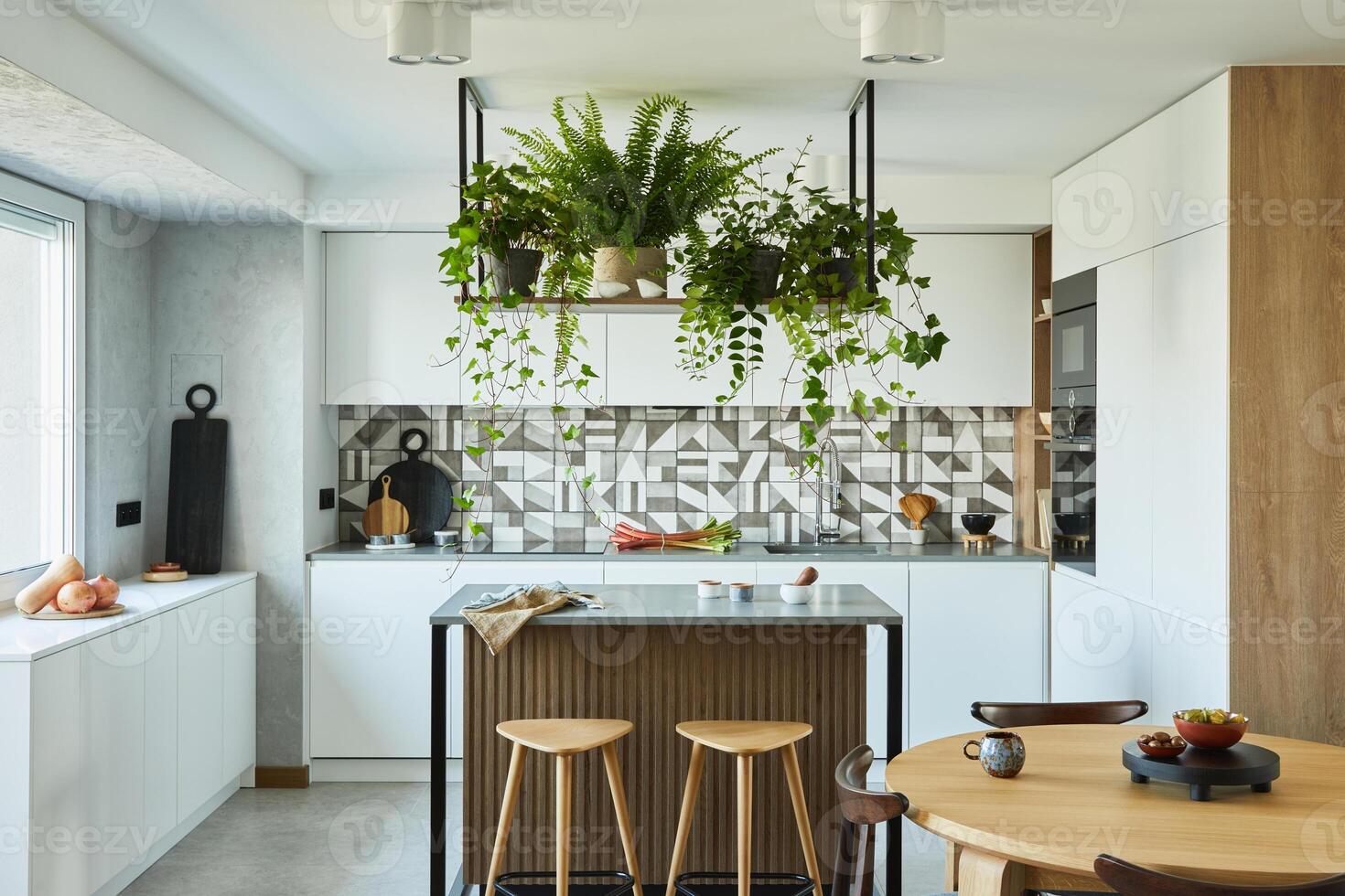 Stylish kitchen interior design with dining space. Workspace with kitchen accessories on the back ground. Creative walls with woode pannels. Minimalistic style and plant loving concept. photo