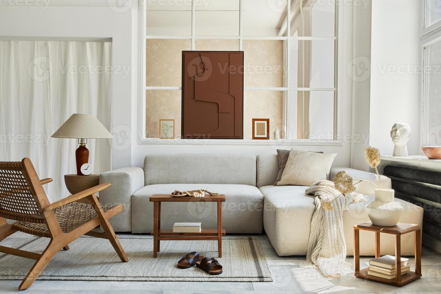 Creative composition of stylish and cozy living room interior with mock up structure painting, grey corner sofa, window, armchair and personal accessories. Beige color. photo
