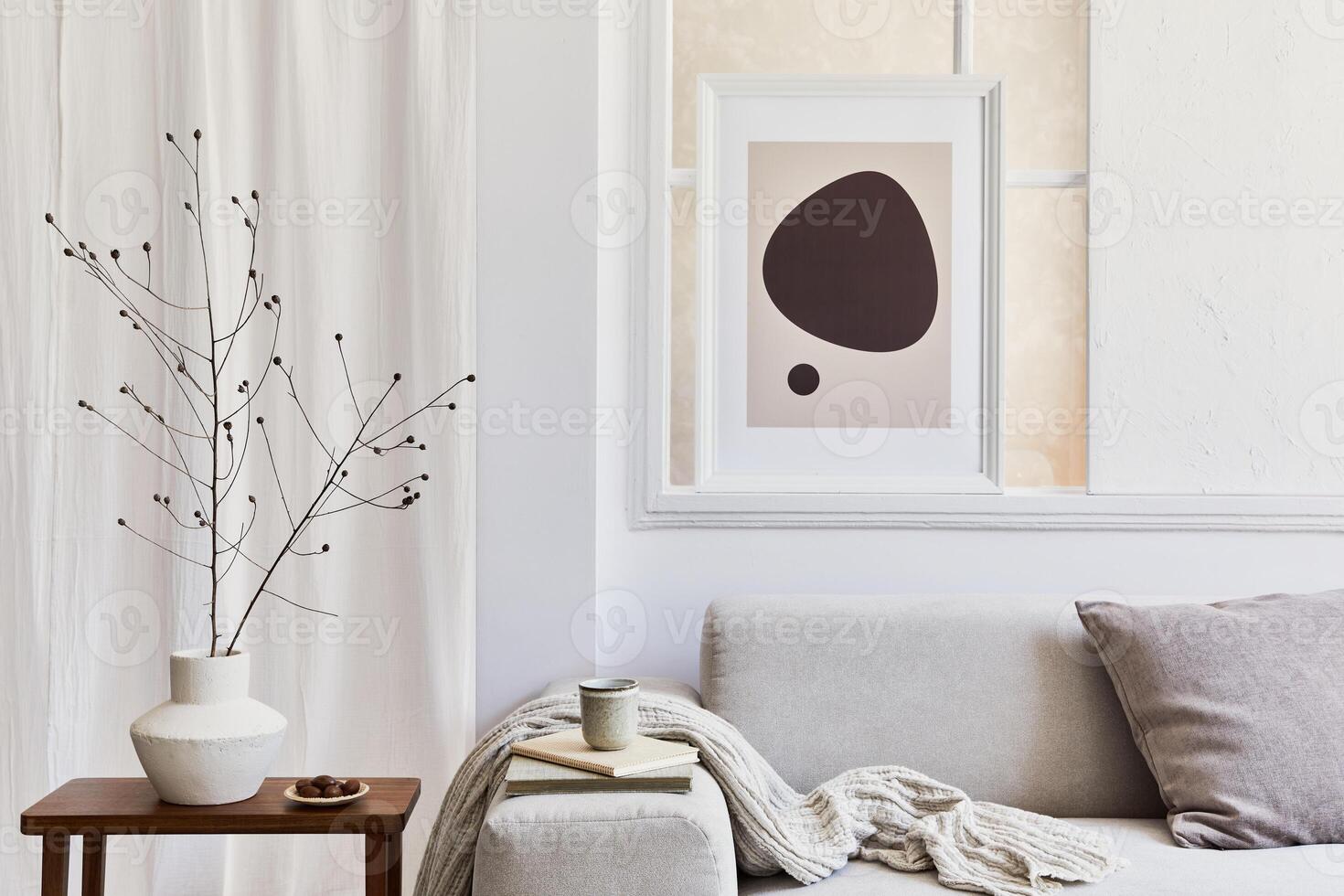 Creative composition of stylish and cozy living room interior with poster frame, grey corner sofa, window, coffee table and personal accessories. Beige neutral colors. photo