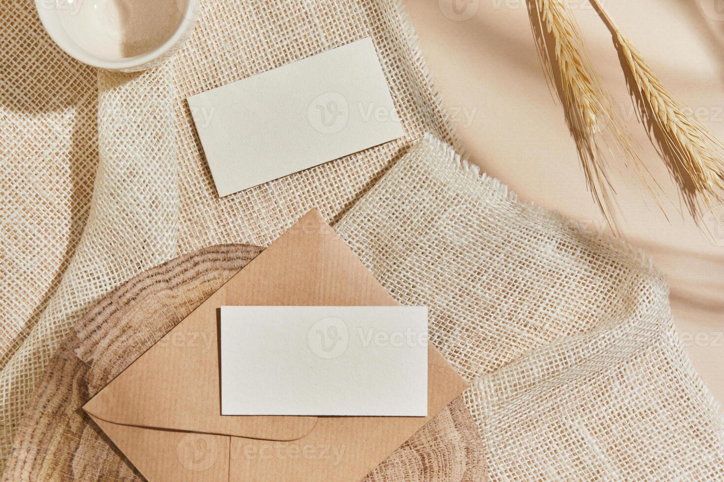 Flat lay of creative interior composition with mock up visit cards, textile, rocks, wood, natural materials, dry plants and personal accessories. Neutral colors, top view, template. photo