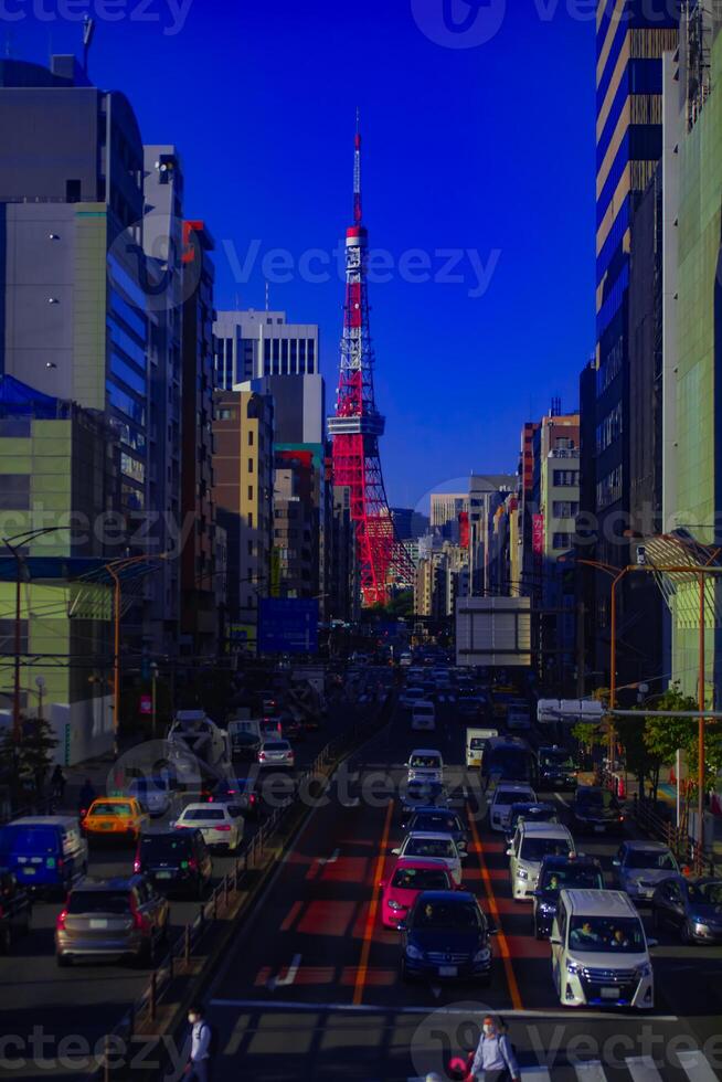A traffic at the urban street behind Tokyo tower vertical shot photo