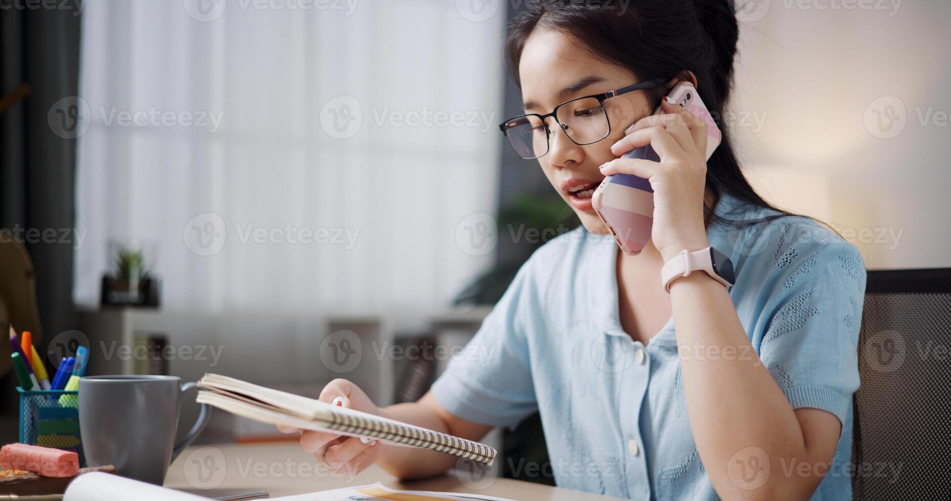 Portrait of Female freelancer sitting at desk explain work to co-workers via mobile phone in home office. photo