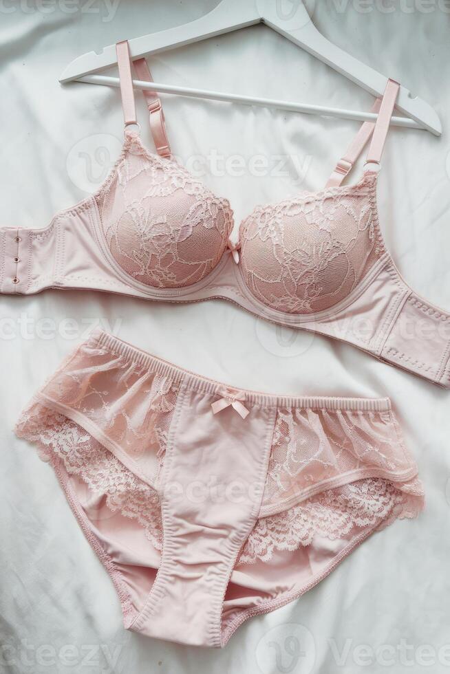 Pink lingerie set displayed on white hanger on bed photo