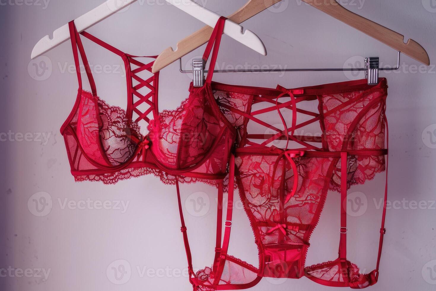 Red lingerie set hanging on wooden hangers bra, panties, and garter belt photo