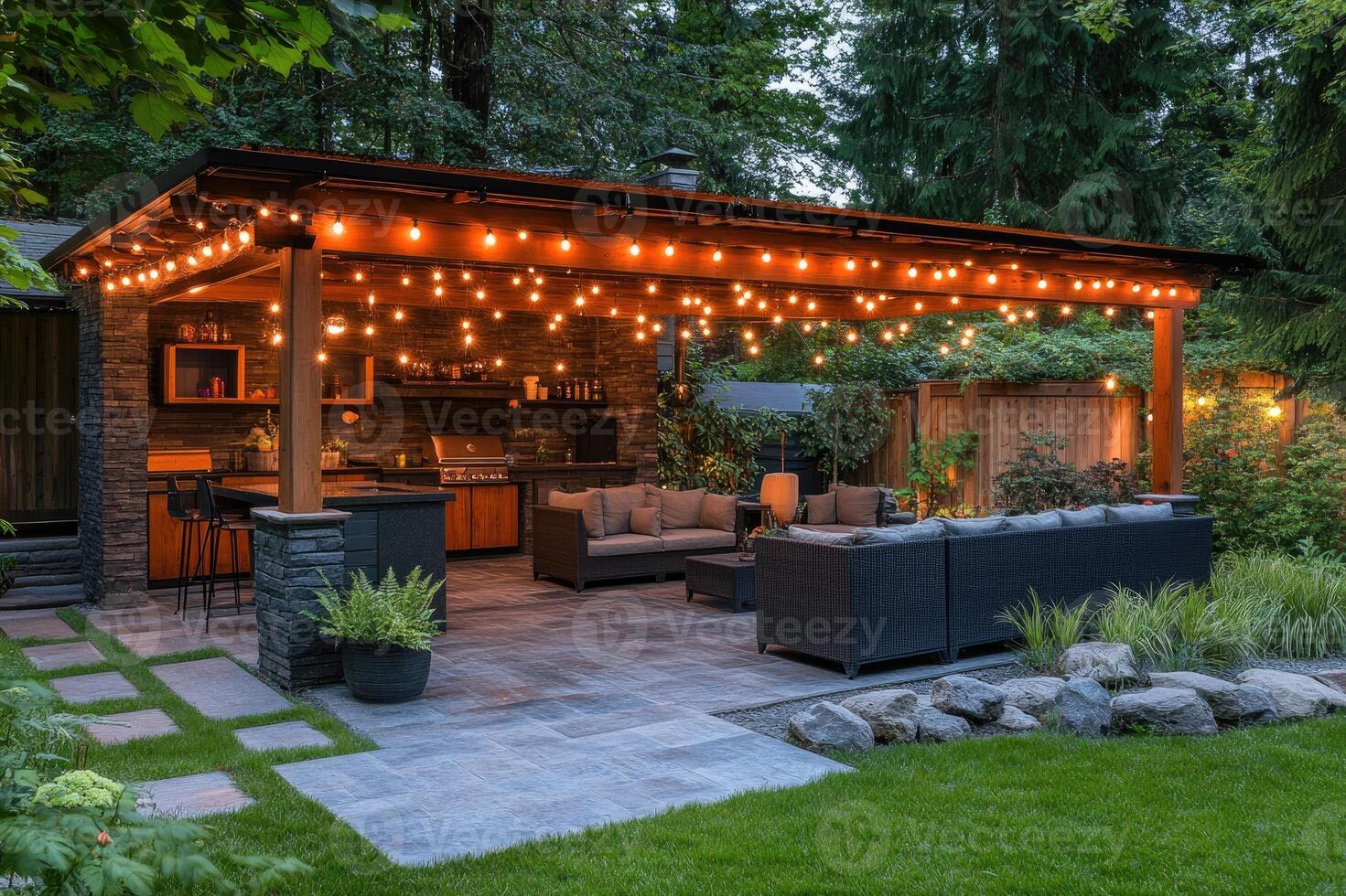 Cozy backyard patio with string lights illuminating outdoor kitchen and lounge area photo