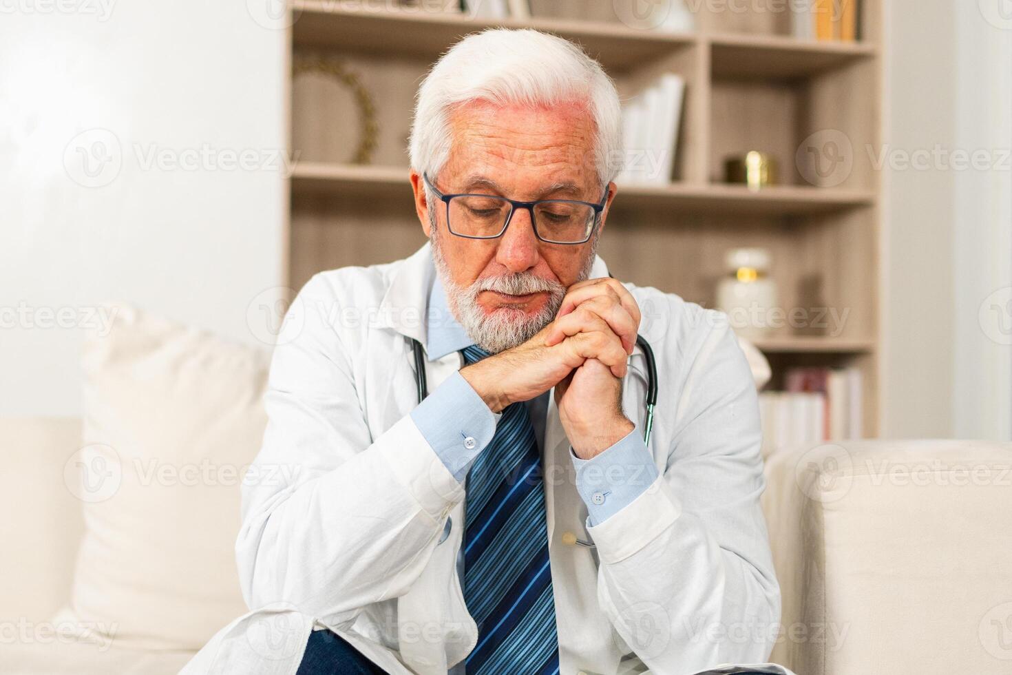 Sad tired mature senior male doctor in medical uniform in hospital or doctor office. Unhappy General Practitioner GP therapist professional healthcare expert in clinic. Healthcare concept photo
