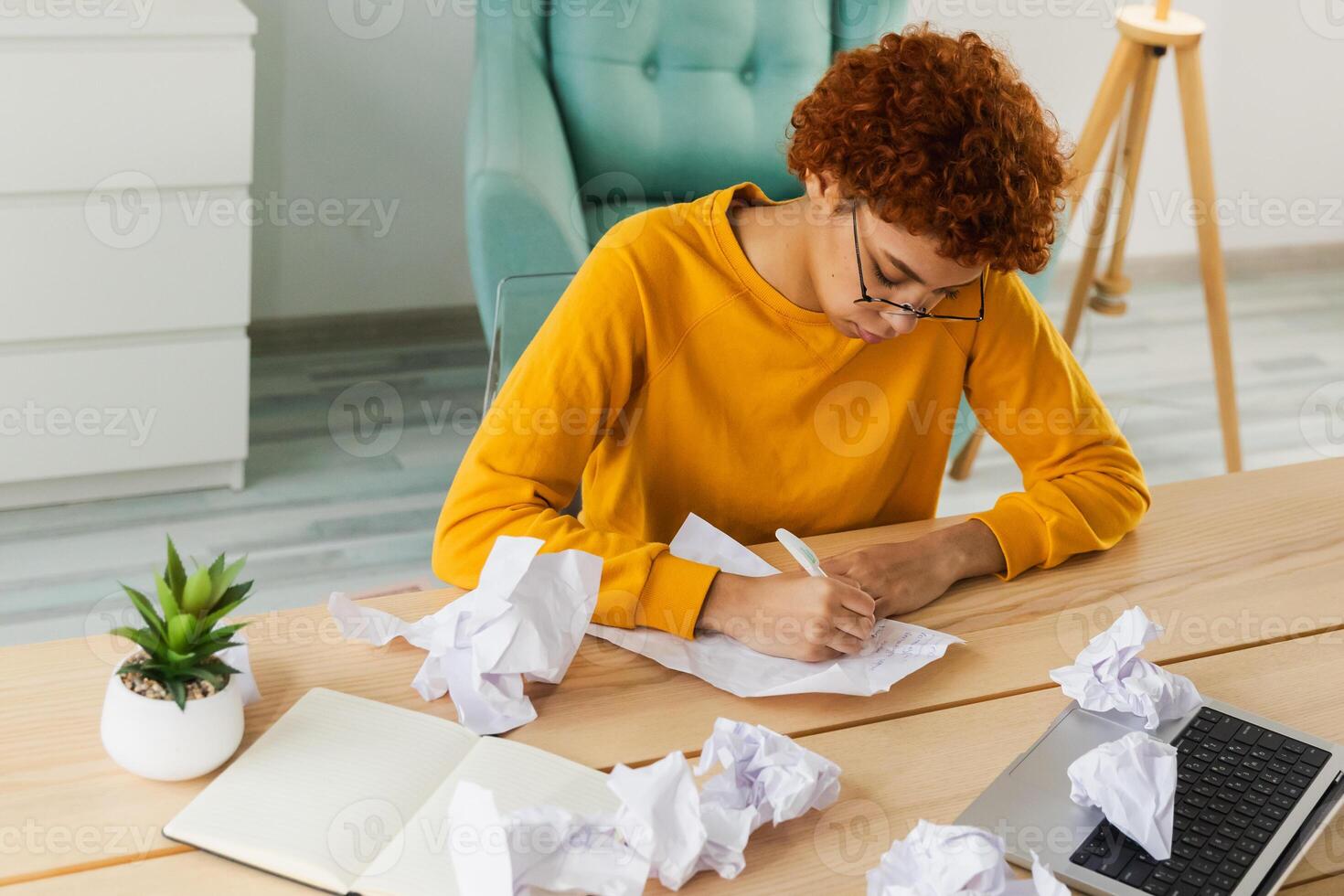 Serious African woman with crumpled paper having problem writing by hand document studying learning at home. Girl no idea sitting at workplace writing notes at office. Start up business deadline photo