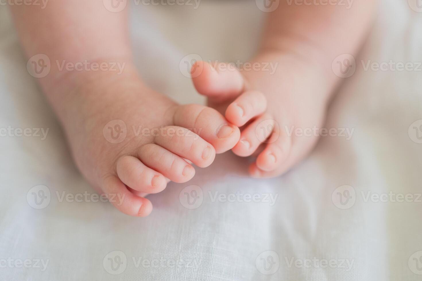 Tiny newborn infant baby feet and toes on white background. Soft newborn baby foot legs under the white blanket. Close up of infant barefeet. Maternity tenderness parenthood birthday. Happy Family photo
