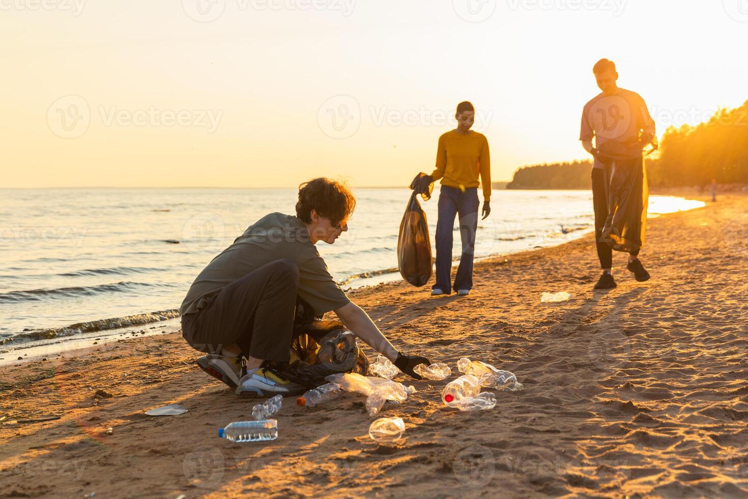 Earth day. Volunteers activists team collects garbage cleaning of beach coastal zone. Woman mans puts plastic trash in garbage bag on ocean shore. Environmental conservation coastal zone cleaning photo