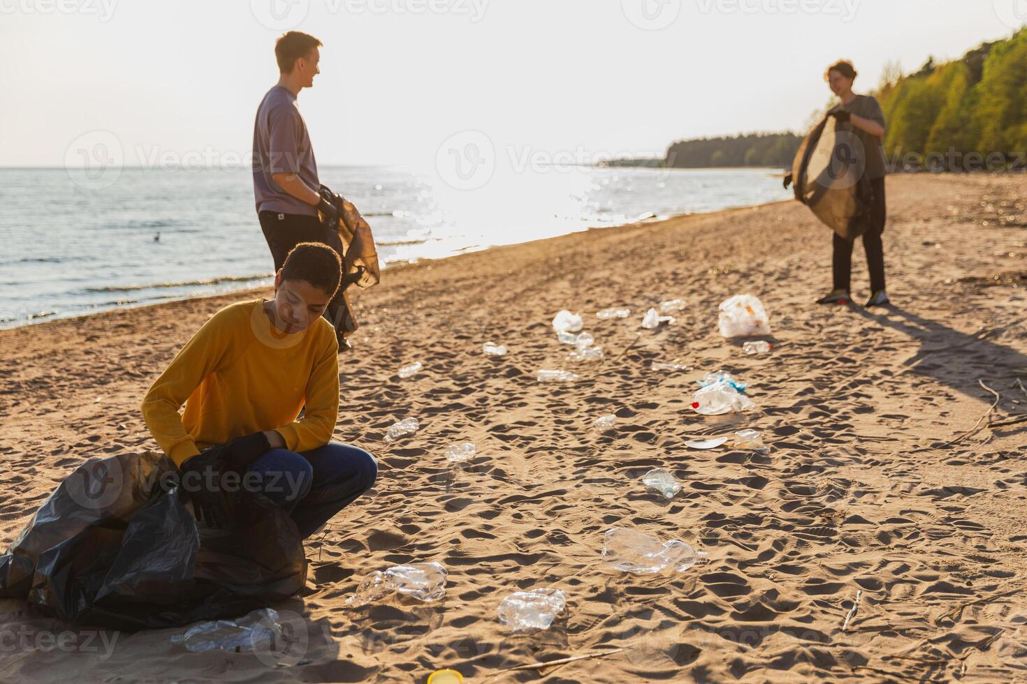 Earth day. Volunteers activists collects garbage cleaning of beach coastal zone. Woman and mans puts plastic trash in garbage bag on ocean shore. Environmental conservation coastal zone cleaning photo
