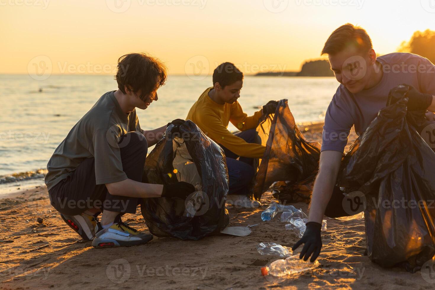 Earth day. Volunteers activists team collects garbage cleaning of beach coastal zone. Woman mans puts plastic trash in garbage bag on ocean shore. Environmental conservation coastal zone cleaning photo