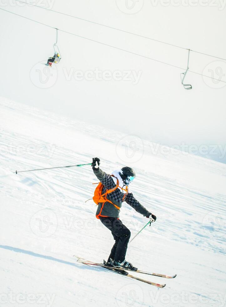 Close up dynamic sports banner of man skier on piste ski downhill fast motion in Alps. Active winter holidays, skiing downhill in overcast day. Ski rides on the track with swirls of fresh snow photo