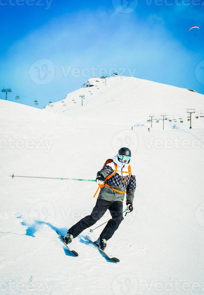 Alpine ski. Front view skiing male skier going downhill on snow covered isolated white ski trail slope piste in winter. Good recreational male skier in white ski jacket and red outfit photo