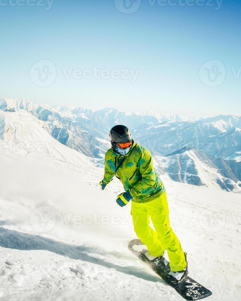 CLOSE UP Extreme snowboarder riding powder and doing hand drag, spraying snow over sun in sunny mountain backcountry. Snowboarder having fun snowboarding in fresh snow off piste photo