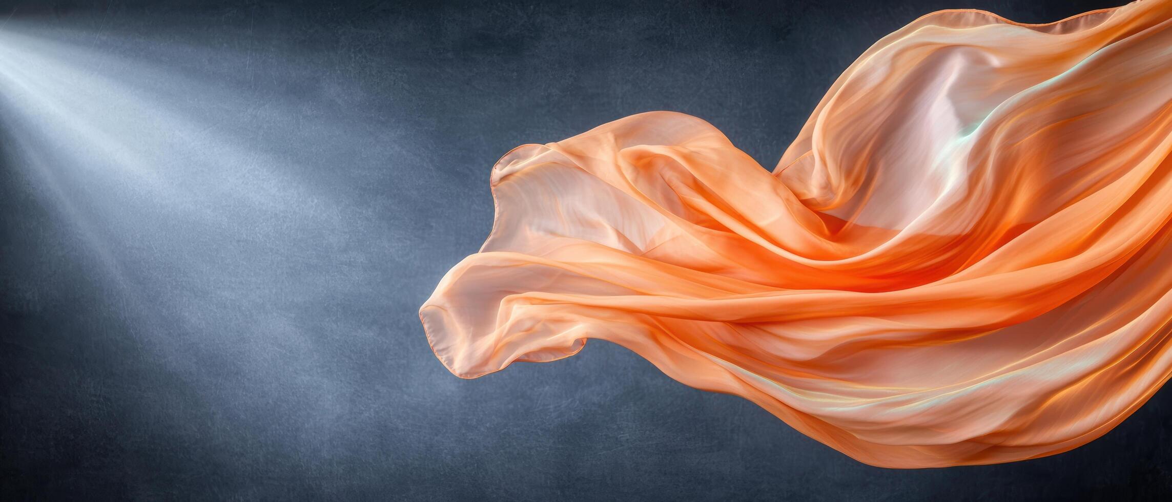 Flowing orange fabric in motion against dark background photo